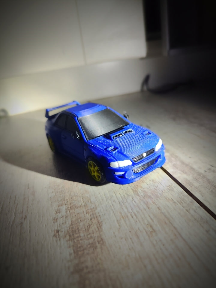 A small blue toy car with yellow wheels, photographed on a light-colored wooden surface with a dark background.